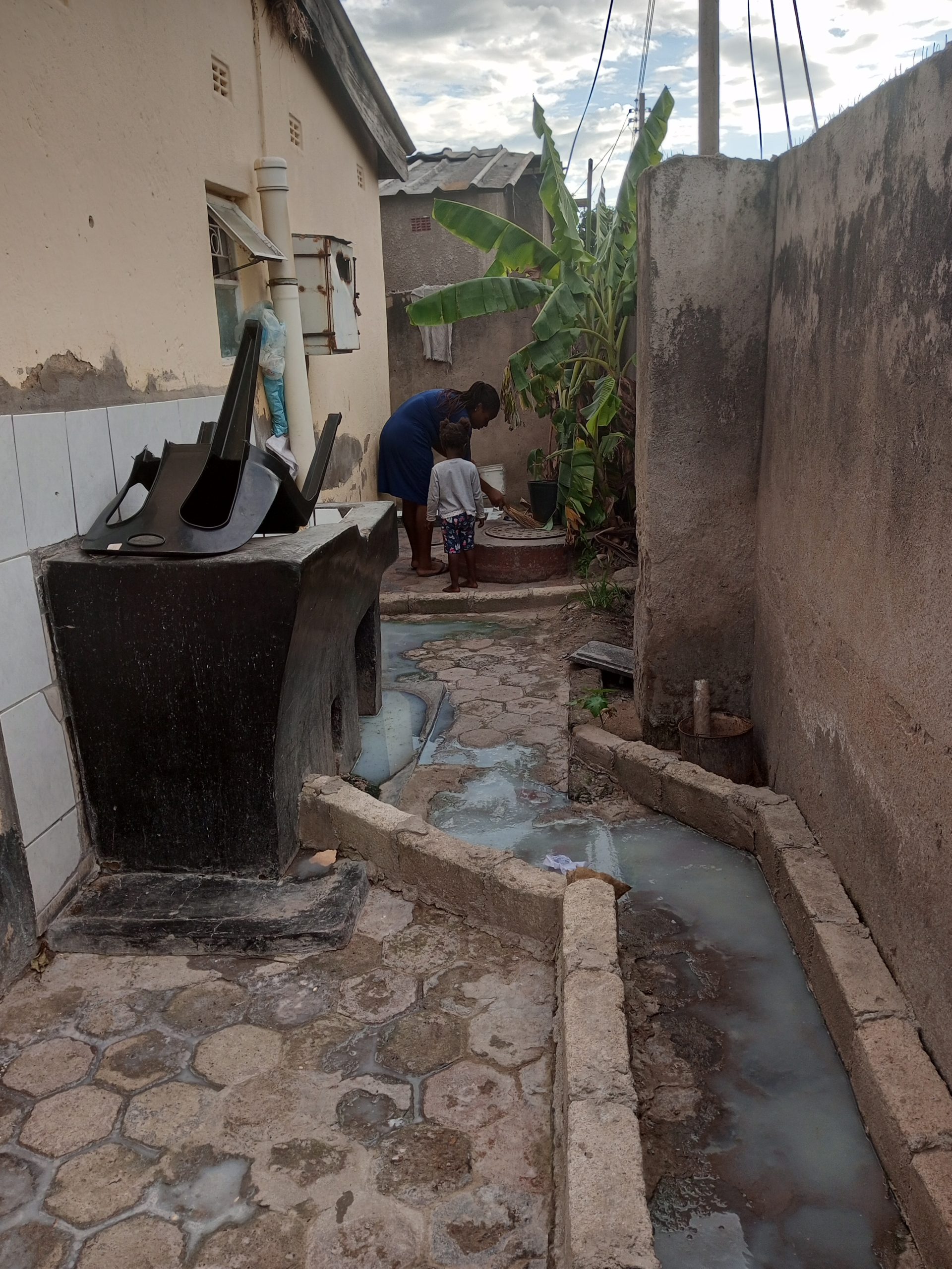 A woman and her child can be seen near a sink overflowing with raw effluent in her home located at Chitungwiza. Photo/ Grace Malahleki/ AWiM