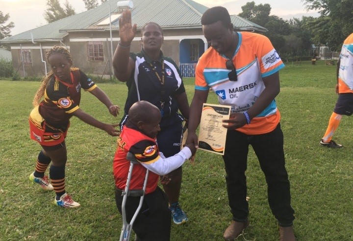 Tug Rugby player Nkundizana Laurent receives a certificate from a coach together with Irankunda Fortunate.